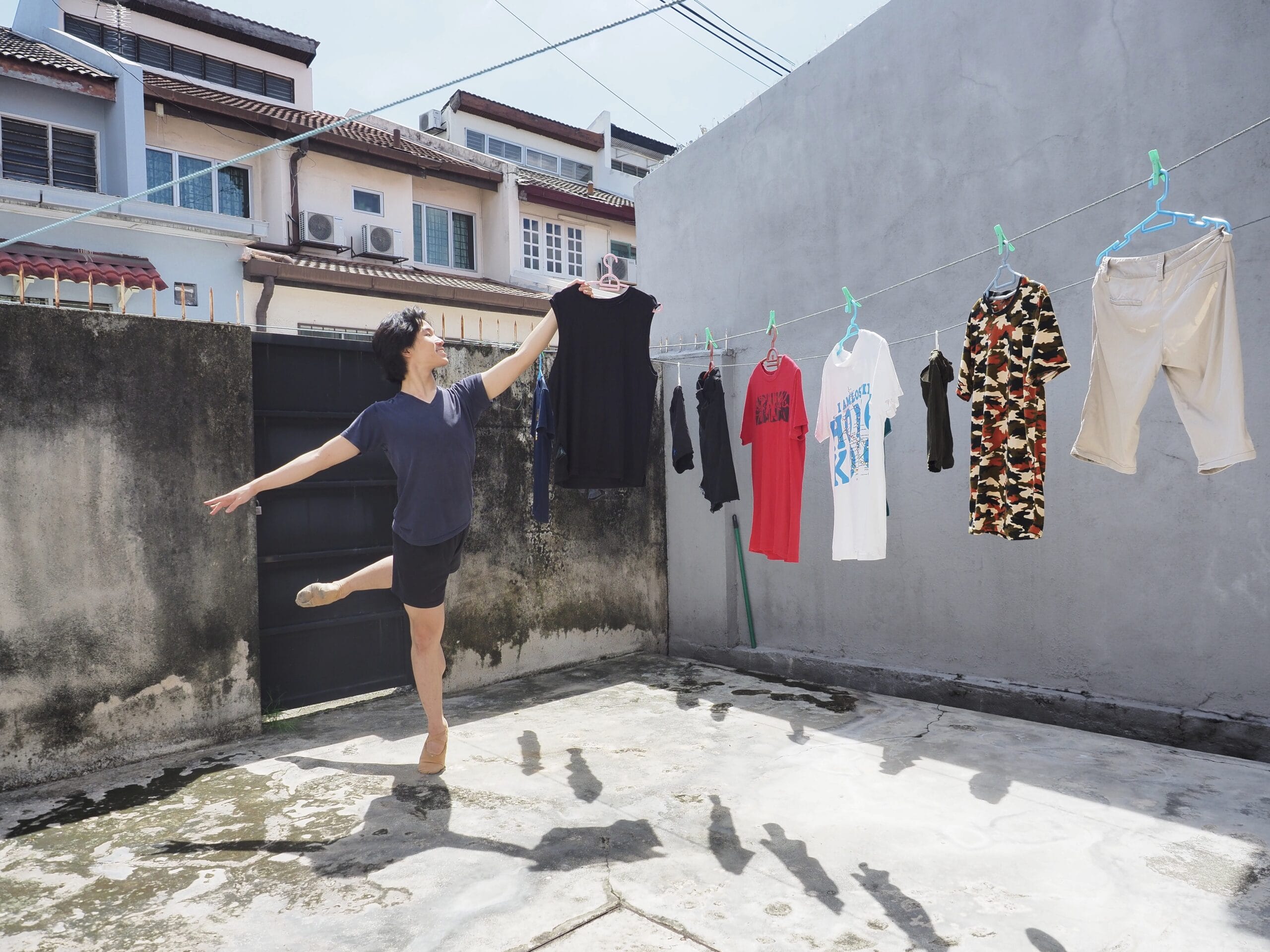 Dancer from home in attitude pose whilst hanging out laundry on clothes line in China